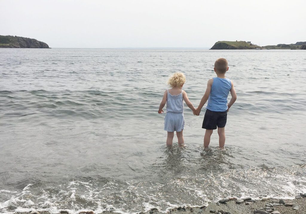 Two kids on the beach in Trinity Bay, Bonavista. Blog post about things to do with kids around Trinity, NL.